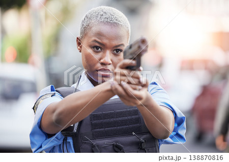 Gun, serious and female police officer in the city for an arrest to stop crime in a street. Upset, young and African woman security guard with pistol for safety, authority and law enforcement in town 138870816