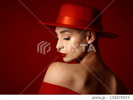 Back, fashion and a model woman on a red studio background for elegant or trendy style. Aesthetic, face and beauty with a young female person in an edgy, classy or unique outfit for a magazine cover Back, fashion and a model woman on a red studio background for elegant or trendy style. Aesthetic, face and beauty with a young female person in an edgy, classy or unique outfit for a magazine cover 138870955