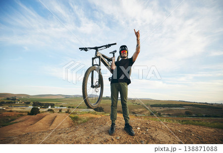Hand sign, mountain bike and man outdoor in nature for extreme sports, training or workout. Rock on, cool attitude and male person with bicycle for off road cycling, countryside travel or adventure 138871088