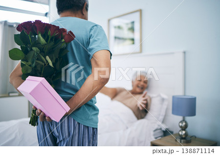 Gift, surprise and a senior couple on their anniversary in the bedroom of their house together for celebration in the morning. Flowers, birthday box and an old man giving his wife a present at home 138871114