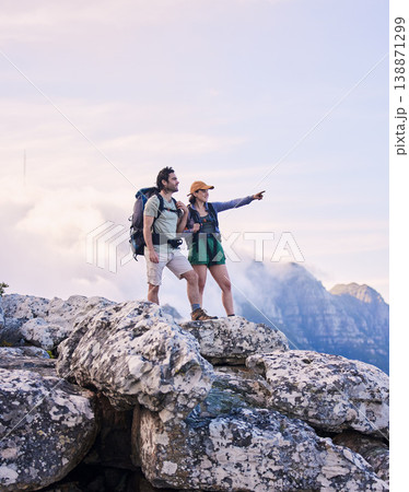Mountains, hiking and pointing, man and woman on peak for adventure in nature, landscape and travel. Outdoor trekking, couple on cliff and relax in scenic clouds for natural journey, view and looking Mountains, hiking and pointing, man and woman on peak for adventure in nature, landscape and travel. Outdoor trekking, couple on cliff and relax in scenic clouds for natural journey, view and looking 138871299