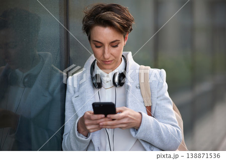 Woman, phone and social media with communication outdoor, chat or email with headphones, travel to work and mockup space. Young creative in city, mobile app with technology and 5g network in Boston Woman, phone and social media with communication outdoor, chat or email with headphones, travel to work and mockup space. Young creative in city, mobile app with technology and 5g network in Boston 138871536