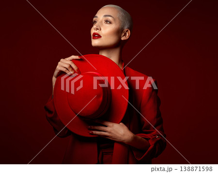 Thinking, fashion and hat with a woman on a red studio background for elegant or trendy style. Vision, art and beauty with a young female model looking edgy or classy in a suit or unique clothes 138871598