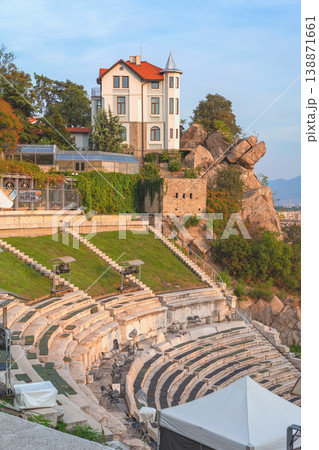 Plovdiv ancient theatre with stone seating, house on rocky hill showing architecture and cultural landmark in Plovdiv Bulgaria. Concept of history heritage travel tourism destination city culture Plovdiv ancient theatre with stone seating, house on rocky hill showing architecture and cultural landmark in Plovdiv Bulgaria. Concept of history heritage travel tourism destination city culture 138871661