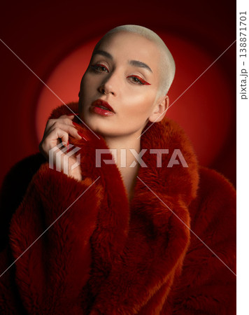 Fashion, portrait and serious woman in a red coat in studio isolated on a background. Face, makeup and confident bald model with cosmetics, aesthetic or style, trendy and fur clothes from Switzerland Fashion, portrait and serious woman in a red coat in studio isolated on a background. Face, makeup and confident bald model with cosmetics, aesthetic or style, trendy and fur clothes from Switzerland 138871701