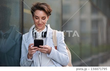 Woman, smartphone and social media with communication in city, chat or email with headphones, travel to work and mockup space. Young creative outdoor, smile at online post with technology in Boston Woman, smartphone and social media with communication in city, chat or email with headphones, travel to work and mockup space. Young creative outdoor, smile at online post with technology in Boston 138871795