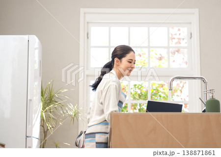ノートパソコンで調理方法を確認しながら料理をする主婦 138871861