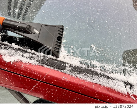 a man cleans a car with a scraper in winter. High quality photo a man cleans a car with a scraper in winter. High quality photo 138872024