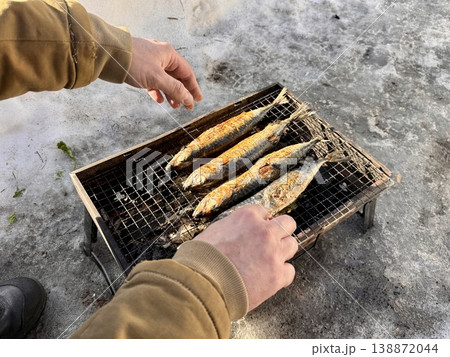 the process of roasting juicy and spiced fresh mackerel on a grill in the fresh air in the park, mackerel on coals on a grill recipe. Photo the process of roasting juicy and spiced fresh mackerel on a grill in the fresh air in the park, mackerel on coals on a grill recipe. Photo 138872044