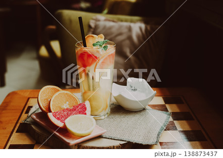A refreshing cold citrus drink made with orange, lemon, and grapefruit, placed on a coffee table, natural light, minimal composition. A refreshing cold citrus drink made with orange, lemon, and grapefruit, placed on a coffee table, natural light, minimal composition. 138873437