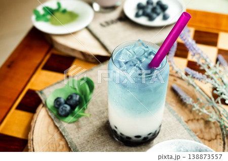 A refreshing blueberry milk drink with a vibrant blue color and whole berries, garnished with mint leaves, blueberries, and matcha powder, natural light, minimal composition. A refreshing blueberry milk drink with a vibrant blue color and whole berries, garnished with mint leaves, blueberries, and matcha powder, natural light, minimal composition. 138873557