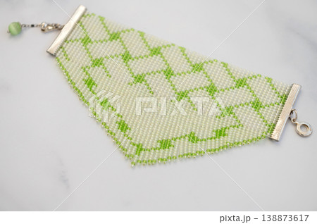 Elegant green and white beaded bracelet on marble surface 138873617