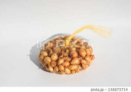 Mesh bag of small onions on white background with shadow Mesh bag of small onions on white background with shadow 138873714