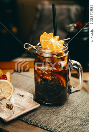 Citrus iced tea with added strawberry juice, decorated with fresh orange served in a glass mug, standing on a coffee table. Natural light, minimalism. Citrus iced tea with added strawberry juice, decorated with fresh orange served in a glass mug, standing on a coffee table. Natural light, minimalism. 138873983