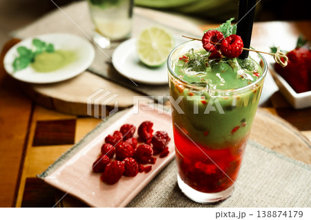 Frozen matcha in the glass with fresh raspberry juice, decorated with fresh natural raspberries. Standing on the wooden coffee table Frozen matcha in the glass with fresh raspberry juice, decorated with fresh natural raspberries. Standing on the wooden coffee table 138874179