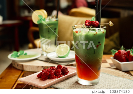 Frozen matcha in the glass with fresh raspberry juice, decorated with fresh natural raspberries. Standing on the wooden coffee table Frozen matcha in the glass with fresh raspberry juice, decorated with fresh natural raspberries. Standing on the wooden coffee table 138874180