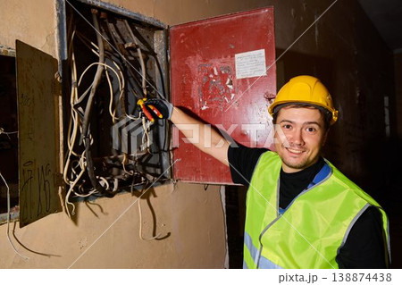 Electrical worker assesses damaged panels in corridor scene Electrical worker assesses damaged panels in corridor scene 138874438