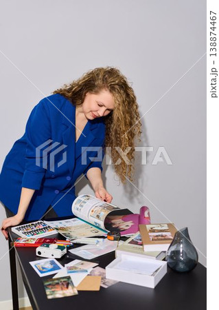 Woman studying glossy magazine pages with focus and precision at workspace Woman studying glossy magazine pages with focus and precision at workspace 138874467