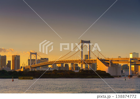 Tokyo, Japan - Oct 13 2024, panoramic view of Tokyo Bay with a cable-stayed Rainbow Bridge above it, a boat and a water bus sailing, at sunset, Tokyo, Japan 138874772