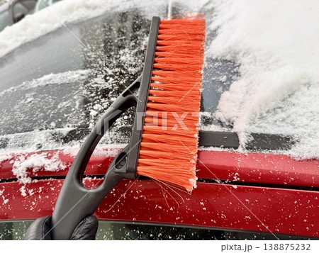 car brush with a scraper in black and orange on a background of snow-white snow on a car in winter car brush with a scraper in black and orange on a background of snow-white snow on a car in winter 138875232