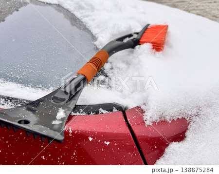 car brush with a scraper in black and orange on a background of snow-white snow on a car in winter car brush with a scraper in black and orange on a background of snow-white snow on a car in winter 138875284
