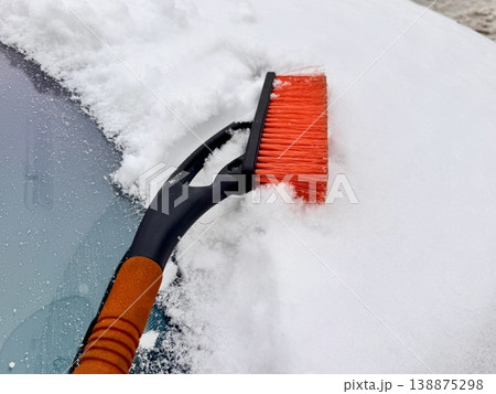car brush with a scraper in black and orange on a background of snow-white snow on a car in winter car brush with a scraper in black and orange on a background of snow-white snow on a car in winter 138875298