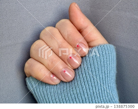 spring manicure for short nails with highlights and a small design at home, a girl's hand on a monochrome background 138875300