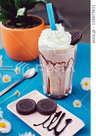 Chocolate smoothie with a creamy flavor in a glass on a wooden table, decorated with chocolate cookies, healthy summer drink, vibrant colors, natural light. Chocolate smoothie with a creamy flavor in a glass on a wooden table, decorated with chocolate cookies, healthy summer drink, vibrant colors, natural light. 138875631