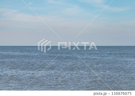 Calm sea horizon with small boat and blue sky Calm sea horizon with small boat and blue sky 138876075