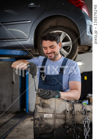 Mechanic repairing a car gearbox in a workshop Mechanic repairing a car gearbox in a workshop 138876248
