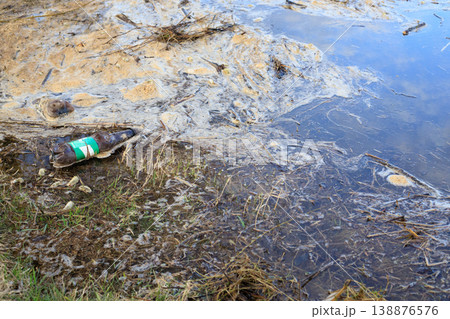 Water pollution. Plastic bottles and dirty foam on the surface of the water. 138876576