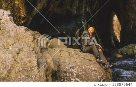 Man Adventurer Resting on Cliff inside Cave Man Adventurer Resting on Cliff inside Cave 138876644