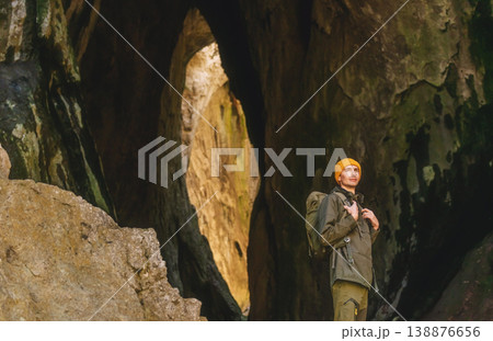 Man hiker with tourist backpack standing inside cave 138876656