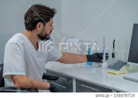 Dark-haired young dentist in his office looking confident and busy 138876719