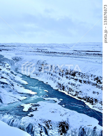 Stunning winter landscape of a frozen canyon river with snow-covered rocks and waterfall. 138876873