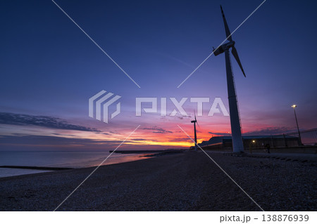 Sunset along coast with pair of land-based wind turbines 138876939