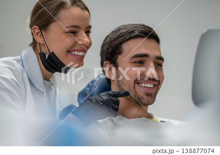 Dentist and patient admiring result in mirror Dentist and patient admiring result in mirror 138877074