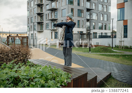 Woman stands on wooden platform while pointing in outdoor space near modern buildings Woman stands on wooden platform while pointing in outdoor space near modern buildings 138877241