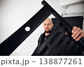 Man holds black chair in a bright indoor space while posing for a photo during daylight 138877261