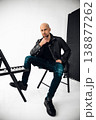 Man posing on chairs in studio setting with simple background in indoor space 138877262
