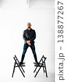 Man stands on two chairs in a studio with white background during a creative session 138877267