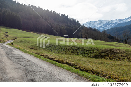 Countryside road leading through green meadow toward mountains Countryside road leading through green meadow toward mountains 138877409