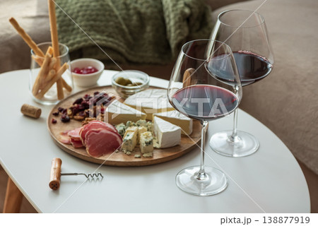 Cozy living room with two glasses of red wine and cheese on table Cozy living room with two glasses of red wine and cheese on table 138877919