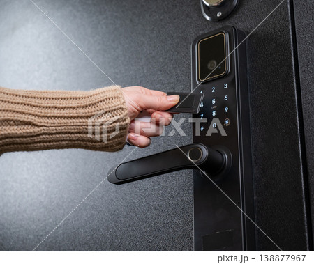A woman opens a modern smart door lock using a contactless key. 138877967