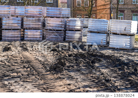 Square before reconstruction with stacked paving stone pallets and muddy tire tracks in urban area Square before reconstruction with stacked paving stone pallets and muddy tire tracks in urban area 138878024