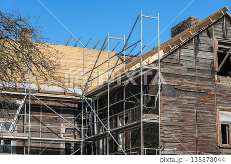 Close view of old wooden house renovation with scaffolding and new timber roof structure Close view of old wooden house renovation with scaffolding and new timber roof structure 138878044