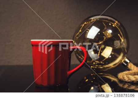 A red coffee cup sits on a table next to a glass sphere A red coffee cup sits on a table next to a glass sphere 138878106