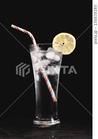 A glass of water with a straw and a lemon slice in it A glass of water with a straw and a lemon slice in it 138878165