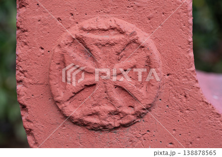 Close-up of a red painted Bolnisi cross relief on a textured stone surface with bokeh background Close-up of a red painted Bolnisi cross relief on a textured stone surface with bokeh background 138878565