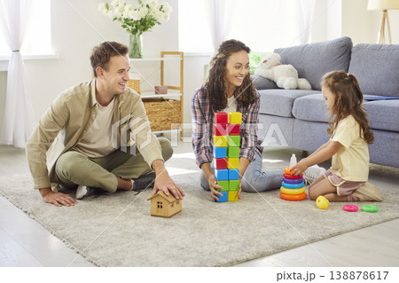 Parents and daughter building wooden toys on living room floor during family time Parents and daughter building wooden toys on living room floor during family time 138878617